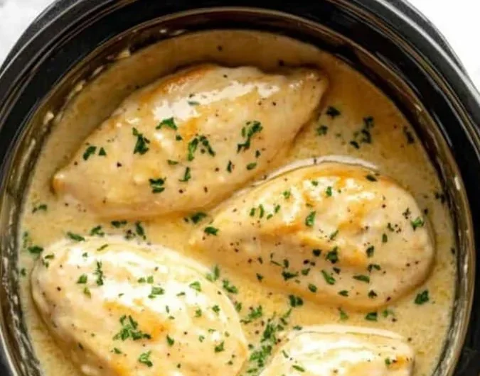 Crockpot creamy garlic parmesan chicken plated with herbs and side dishes