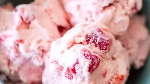 Creamy homemade strawberry ice cream topped with fresh strawberries