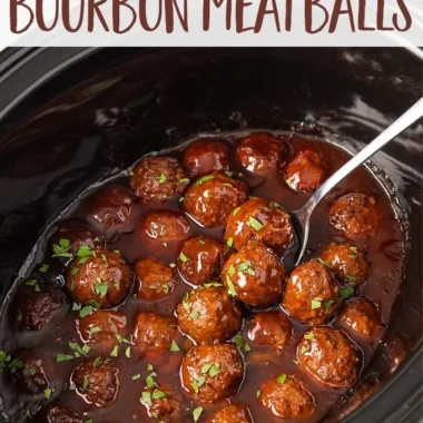 Slow cooker bourbon meatballs served in a bowl with sauce and herbs.