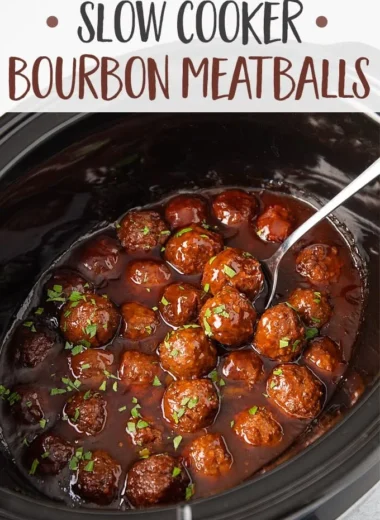 Slow cooker bourbon meatballs served in a bowl with sauce and herbs.