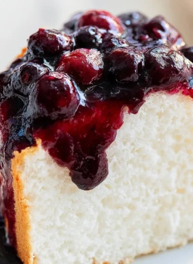 A slice of fluffy Angel Food Cake on a white plate topped with fresh berries