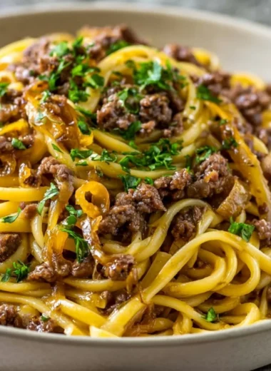 A plate of garlic butter beef pasta garnished with herbs