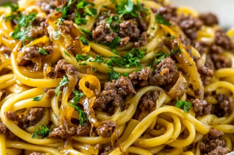 A plate of garlic butter beef pasta garnished with herbs