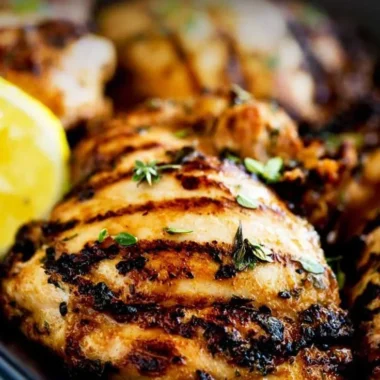 Grilled apple cider thyme chicken on a plate garnished with herbs.