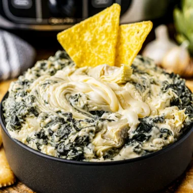Creamy crock pot spinach artichoke dip served with crunchy bread slices