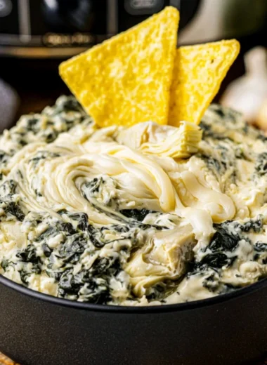 Creamy crock pot spinach artichoke dip served with crunchy bread slices