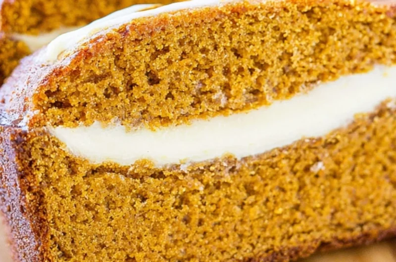 Loaf of cozy pumpkin bread with cream cheese frosting on a wooden cutting board