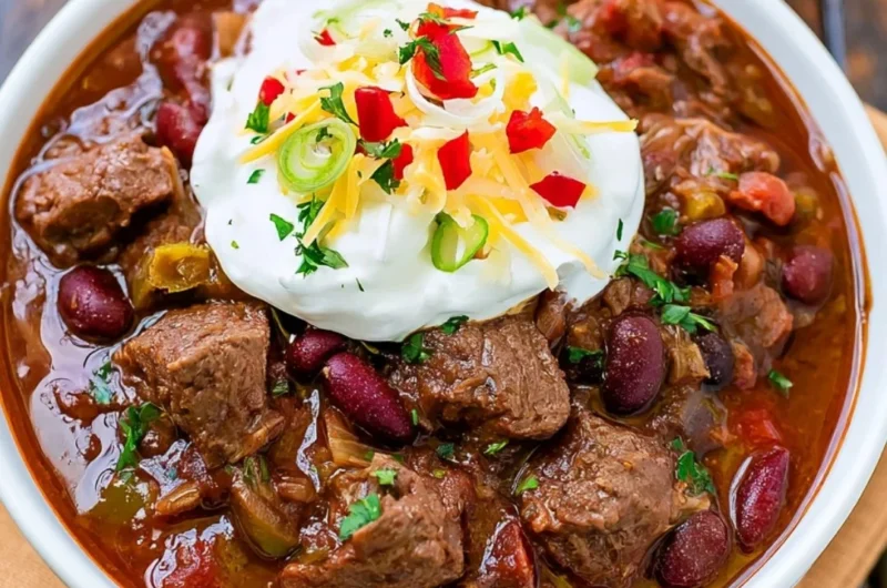 Delicious bowl of spicy steak chili garnished with fresh herbs