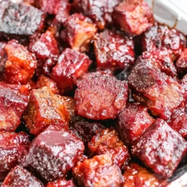 Delicious Poor Man's Burnt Ends served on a plate with BBQ sauce and sides.
