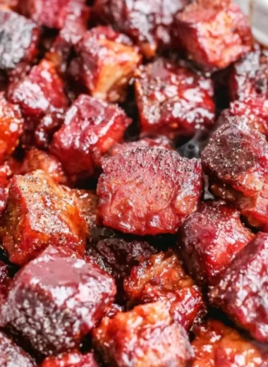 Delicious Poor Man's Burnt Ends served on a plate with BBQ sauce and sides.