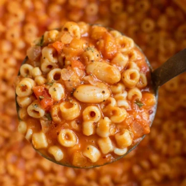 Bowl of hearty Pasta Fagioli Soup with beans and pasta garnished with herbs.