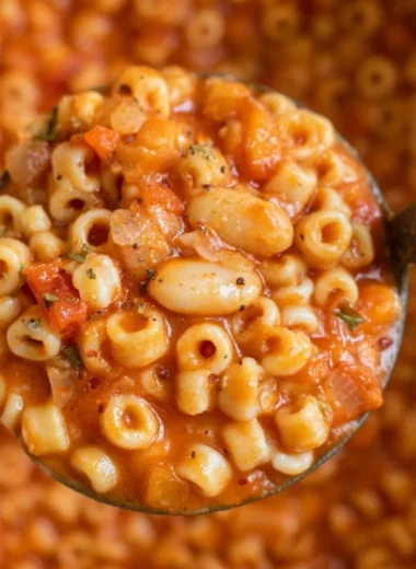 Bowl of hearty Pasta Fagioli Soup with beans and pasta garnished with herbs.